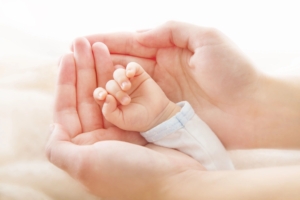 Adult hand cupping an infant's hand
